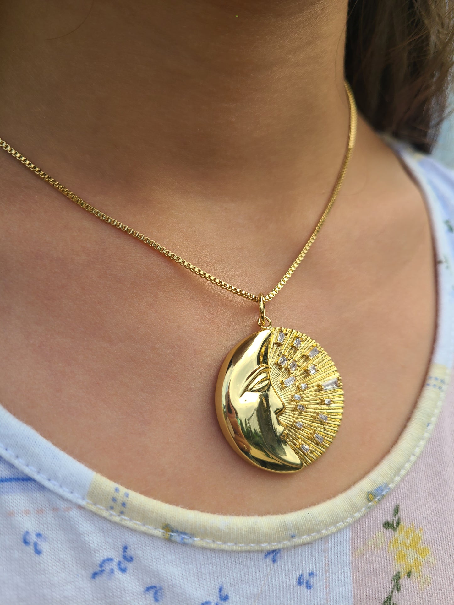 Cadena con dije de sol y luna dorado.